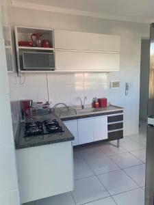 a white kitchen with a stove and a microwave at Ed. Odilon Vieira ap.205 in Vitória da Conquista