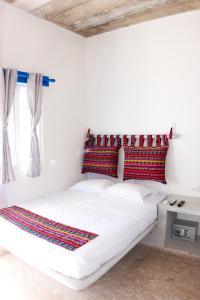 a bedroom with a white bed with red pillows and a window at Burí Hotel in Monterrico