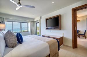 um quarto com uma cama grande e uma televisão de ecrã plano em Royalton Grenada, An Autograph Collection All-Inclusive Resort em Bamboo