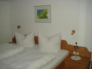2 camas con almohadas blancas y una foto en la pared en Apartment Sutterlüty, en Bezau