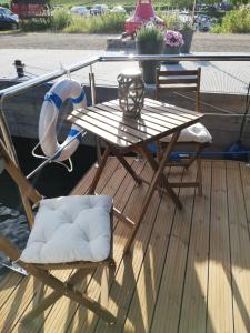 a wooden deck with a table and chairs on a boat at Hausboot auf der Mosel in Pölich