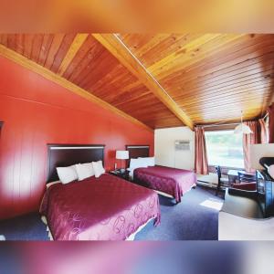 1 dormitorio con 2 camas y pared roja en The Crossroads Motel, en Elkhorn