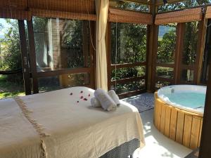 a bedroom with a tub and a bed with towels at Pousada Watu Kerere in Praia do Rosa