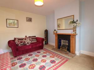 a living room with a red couch and a fireplace at Isadore Cottage in Horncastle