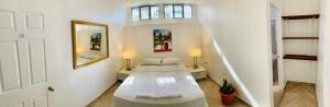 a white room with a bed and a mirror at Palmira Hostel in Tegucigalpa