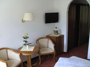 a room with two chairs and a table and a tv at Hotel Annabell in Merano