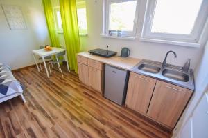 a kitchen with wooden cabinets and a sink and a table at Regem Apartments Płońska in Warsaw