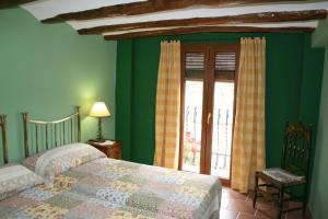 1 dormitorio con paredes verdes, 2 camas y ventana en La Casa del Azafrán, en Villanueva del Rebollar de la Sierra