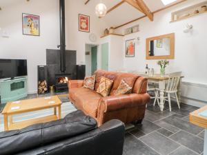 a living room with a leather couch and a fireplace at The Old Haybarn in Newton Abbot