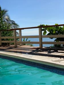 una piscina con una recinzione e l'oceano sullo sfondo di Villa Dei Fiori a São Sebastião