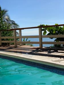 a pool with a fence and the ocean in the background at Villa Dei Fiori in São Sebastião