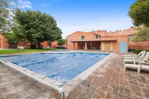 a swimming pool with two chairs and a building at Acogedora Suite Alberca Bernardo Quintana 3B in Mendiola