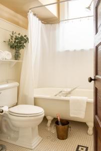 a white toilet sitting next to a bath tub in a bathroom at The Sacajawea Hotel in Three Forks