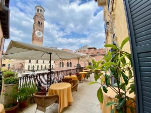 a balcony with tables and a clock tower at Hotel Aurora in Verona