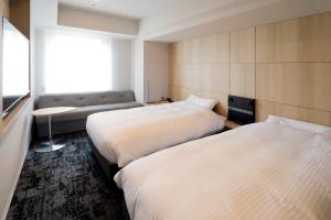 a hotel room with two beds and a couch at JR Inn Sapporo Kita 2 Jo in Sapporo