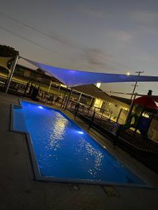 a swimming pool with blue lights in front of a fence at Sunshine Gardens Bourke Resort in Bourke
