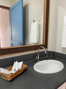 um balcão de casa de banho com um lavatório e um espelho em Sítio Tamanduá em Brotas
