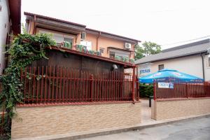 un edificio con una valla roja y una sombrilla azul en Casa Ștefan en Eforie Sud