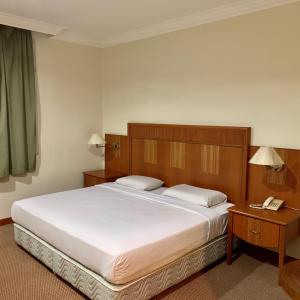 a bedroom with a large white bed and two tables at New Grand Hotel in Keningau