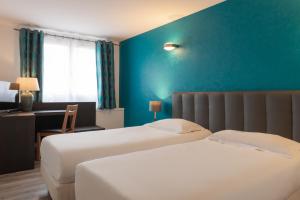 two beds in a hotel room with a blue wall at Hôtel de l'Orme, Akena in Évreux