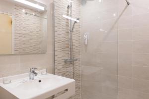 a white bathroom with a sink and a shower at Hôtel de l'Orme, Akena in Évreux