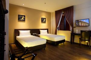 a hotel room with two beds and a desk at Kimberley Hotel Georgetown in George Town