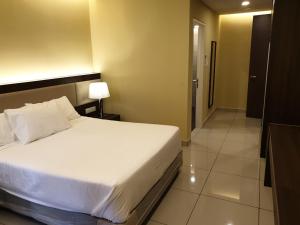 a bedroom with a white bed and a bathroom at Studio Suite Genting Highland 33 in Genting Highlands