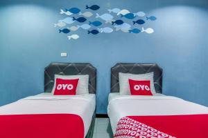 two beds in a room with fish on the wall at OYO 428 Pha Mansion in Chachoengsao