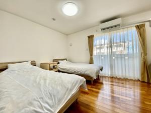 sypialnia z 2 łóżkami i oknem w obiekcie M-Villaggio Miyakojima w mieście Miyako-jima