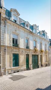 a large building with green doors on a street at L'Atelier Corval in Le Mans