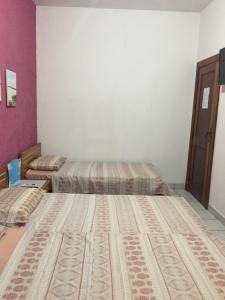 2 łóżka w pokoju z fioletowymi ścianami w obiekcie Pousada da Didi w mieście Belém