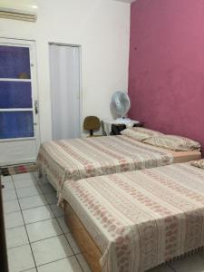 2 łóżka w pokoju z różową ścianą w obiekcie Pousada da Didi w mieście Belém
