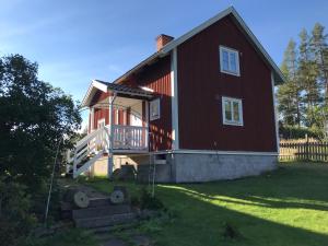 uma grande casa vermelha com um alpendre e um quintal em Högetorp em Oskarshamn