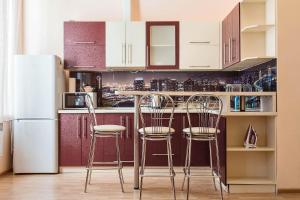 a kitchen with a counter with three bar stools at Apartments Etazh in Odesa