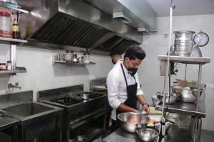 a man standing in a kitchen preparing food at Hotel Hamilton in Zirakpur