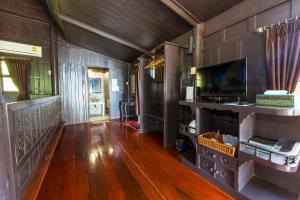 a living room with a wooden floor and a television at Koh Talu Island Resort in Bang Saphan Noi