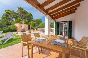 a patio with a wooden table and chairs at Villa Alcaufar in S'Algar