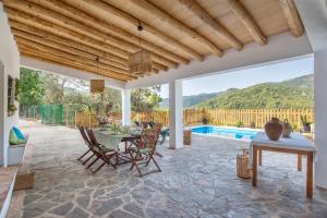 eine Terrasse mit einem Tisch, Stühlen und einem Pool in der Unterkunft Casa Rural Monte Dios in Jubrique