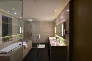 y baño con 2 lavabos, bañera y ducha. en Holiday Inn New Delhi International Airport, an IHG Hotel, en Nueva Delhi