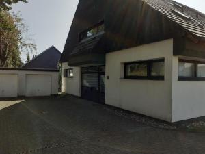 a white house with a black roof and a driveway at Ferienwohnung JuLe in Winterberg