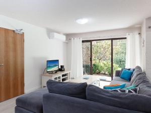 un soggiorno con un divano blu e una TV di Bay Parklands 57 ground floor unit with pool tennis court and aircon a Nelson Bay