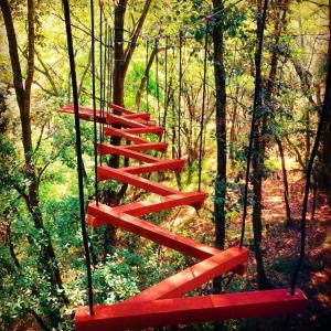 a swing in a forest with a red staircase at Hotel Villa Xtreme in Villa del Carbón