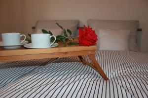 a table with two cups and a flower on a bed at Apartmán Domčeková in Košice
