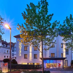 a building with a tree in front of it at Hotel Maximilians in Essen