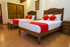 2 camas en una habitación de hotel con almohadas rojas en Posada La Querencia, en Xico