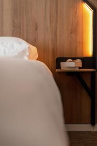 a bedroom with a bed and a night stand with a book at B&B HOTEL Poitiers Aéroport in Poitiers
