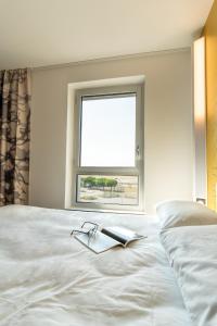 a bed with a book on it with a window at B&B HOTEL Poitiers Aéroport in Poitiers