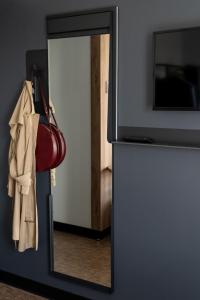 um espelho na frente de uma porta com uma bolsa e um saco em B&B HOTEL Poitiers Aéroport em Poitiers