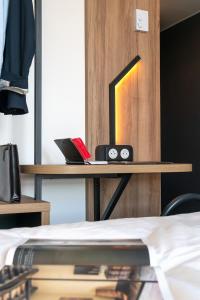 a desk with a laptop on it next to a bed at B&B HOTEL Poitiers Aéroport in Poitiers