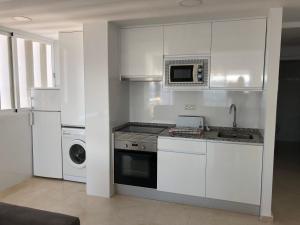 kuchnia z białymi szafkami, kuchenką i kuchenką mikrofalową w obiekcie Torre Levante Plus - Arca Rent w mieście Benidorm